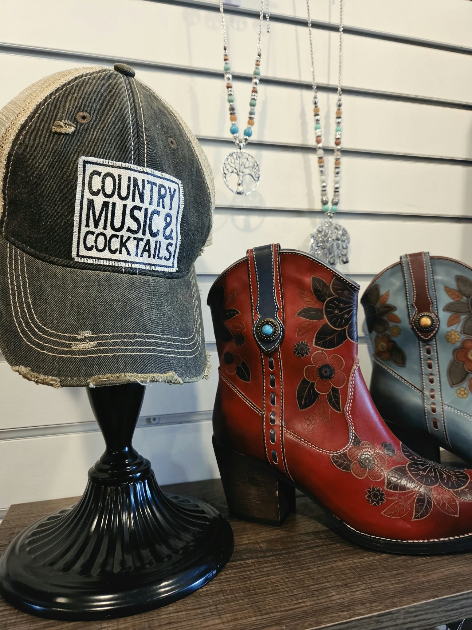 Distressed hat, floral boots and necklaces displayed at Rogue Sole & Style in Grants Pass
